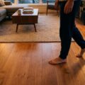 Varm gulvvarme i moderne stue med personer i lyse sokker som illustration af komforten ved gulvvarmeinstallation